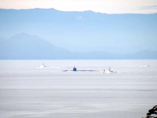 Nuclear submarine being escorted by two Coastguard gunships.